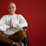 Contribution picture to the article "Yoga and Cancer" - Young woman with short hair meditates in a wheelchair.