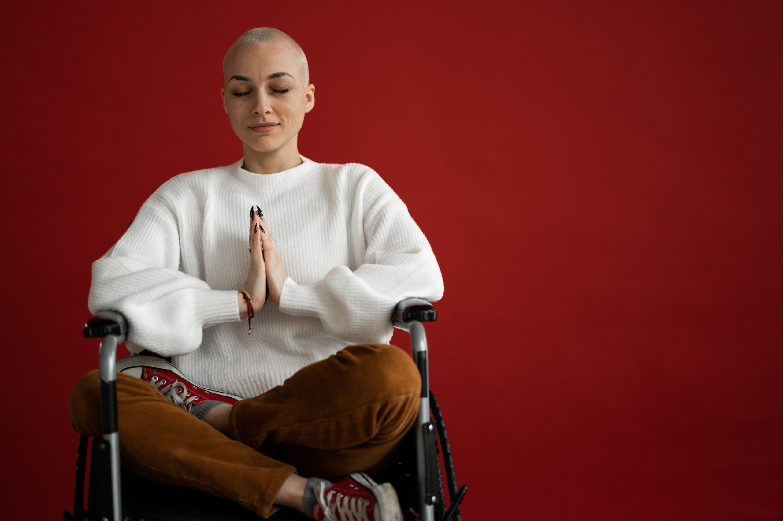 Contribution picture to the article "Yoga and Cancer" - Young woman with short hair meditates in a wheelchair.